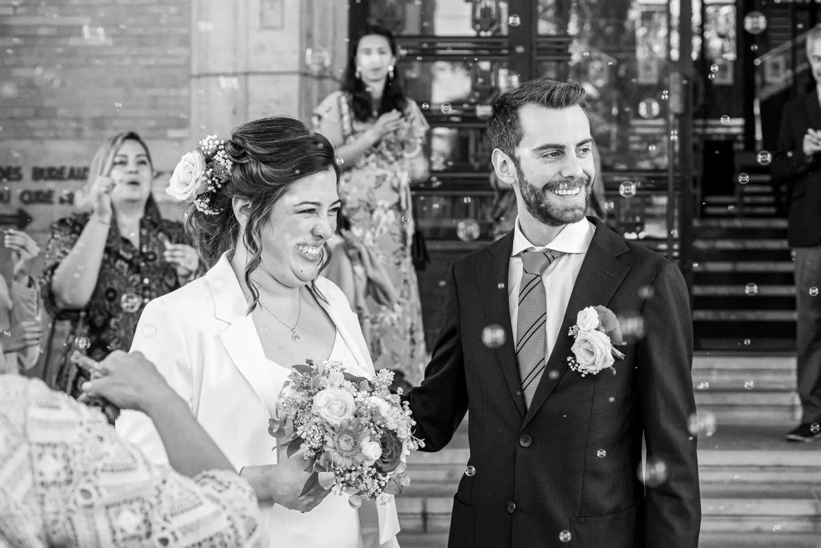 Les mariés sourient à la sortie de leur cérémonie, entourés de bulles