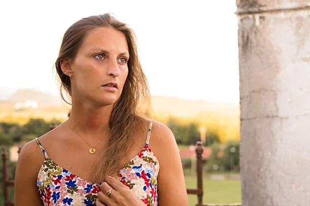 Portrait d’une femme en robe fleurie près d’une colonne en pierre
